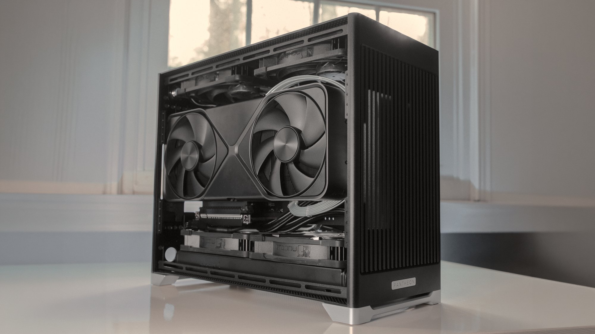A Pantheon on a desk with the side open, showing the graphics card and the drive cages
